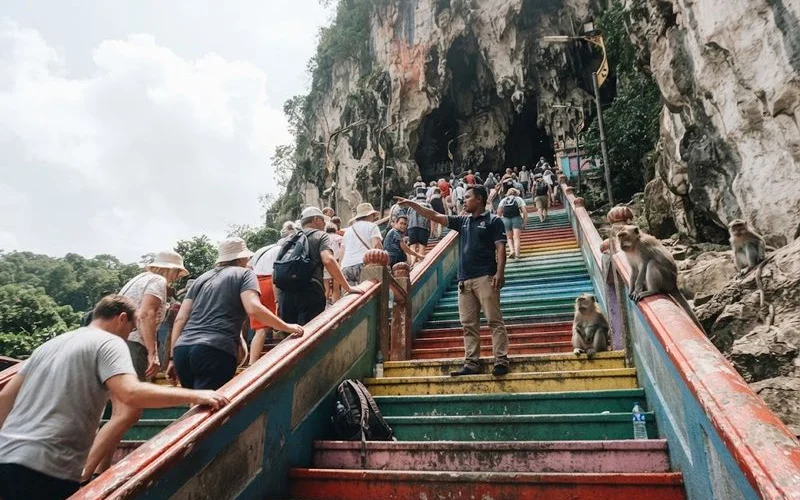 Visitors climbing the colourful staircase toward the main cave temple entrance at Batu Caves near Kuala Lumpur